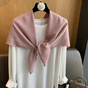 Détail d'une écharpe en coton et lin rose avec strass brillants sur un haut blanc