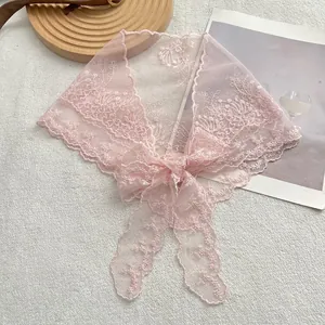 Detail eines rosa Spitzenschals mit Blumenstickerei, Netzstruktur und einer zarten Schleife