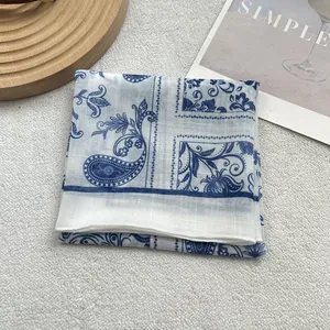 Detailed close-up of folded blue and white floral silk scarf on a textured background
