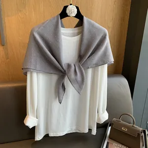 Détail d'un t-shirt blanc à manches longues avec un châle gris orné de strass en coton et lin