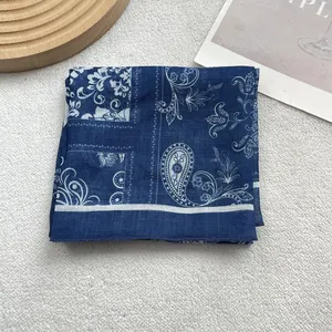 Detail of blue and white paisley pattern scarf on a wooden tray with a minimalist layout