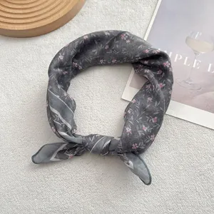 Detail of a knotted gray floral scarf with thin striped edges on a textured background