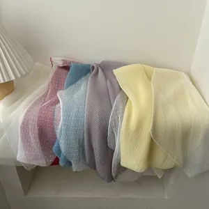 Lightweight pleated long scarves in multiple colors stacked in a modern white niche