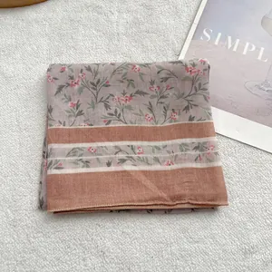 Detail of floral linen square scarf featuring delicate leaf patterns and striped border