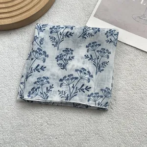 Detailed view of blue floral pattern on white cotton scarf with fine weaving texture