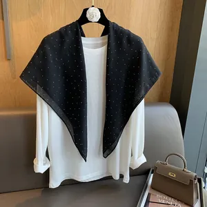 Détail d'une écharpe élégante à pois noirs drapée sur un cintre orné d'un camélia