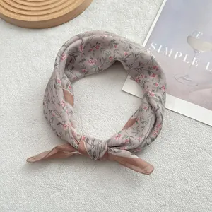 Detail of soft floral cotton scarf with precise edge stitching on a wooden tray