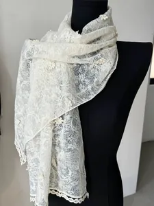 Detailed embroidery on a white lace scarf with floral patterns and scalloped edges
