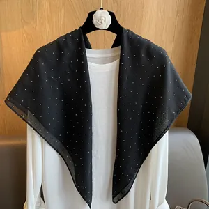 Détail d'une écharpe en coton noir à pois blancs avec des accents en strass brillants
