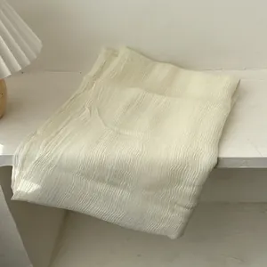 Detail shot of beige long silk scarf with vertical pleated texture and soft material