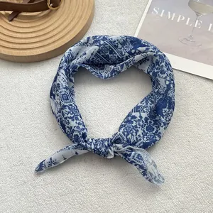 Detail of elegant blue floral silk scarf tied as a stylish headband on neutral fabric