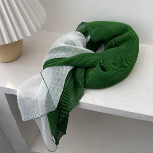 Detail of dark green and white pleated scarf with delicate polka dot texture