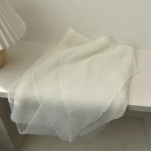 Detail of white lace mesh fabric scarf with delicate diamond texture and pleated edges