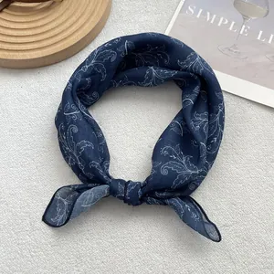 Detailed view of floral paisley pattern on blue silk scarf with fine stitching edges