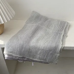 Close-up of light gray pleated scarf with fine vertical texture and soft lavender lining