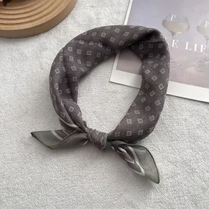 Close-up of small geometric diamond pattern scarf on a soft white plush background