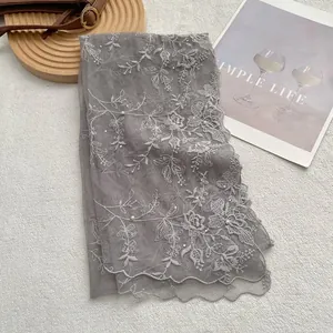 Close-up of grey lace embroidery scarf featuring delicate floral patterns and pearl beads