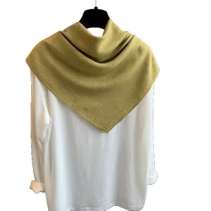 Châle en coton et lin jaune moutarde avec perles blanches sur cintre noir