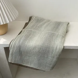Detail of pleated blend scarf with two-tone gradient draped near a pleated lampshade