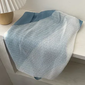 Detail of blue gradient pleated scarf featuring delicate white polka dot mesh overlay