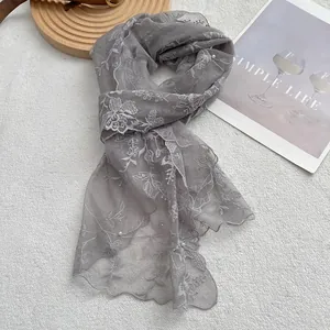 Detail of gray lace scarf with white floral embroidery and delicate pearl embellishments