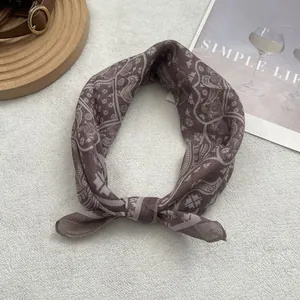 Close-up of brown paisley patterned cotton scarf tied on a minimalist magazine backdrop