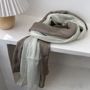 Detail of pleated long scarf in green and brown gradient, soft silk blend fabric