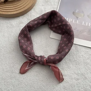 Macro shot of a burgundy geometric pattern silk scarf knotted on a plush grey surface