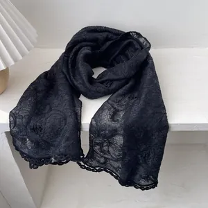 Detail of delicate black hollow lace scarf featuring intricate floral embroidery and scalloped edges