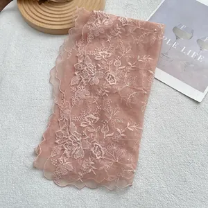 Detail of light pink lace scarf featuring floral embroidery and small white pearls