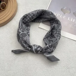 Detail of grey square scarf with vintage paisley print tied on soft faux fur background