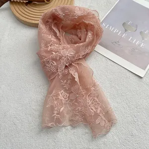 Detail of light pink lace scarf featuring floral embroidery with pearls and rhinestones