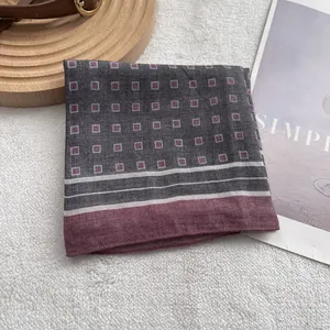 Macro shot of dark grey geometric square scarf with burgundy patterns and striped borders