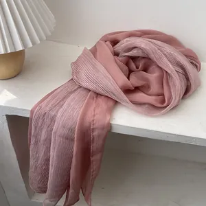 Detail of soft pink pleated scarf with delicate crinkle texture on white display