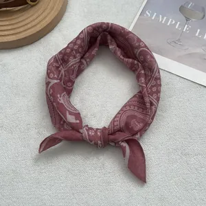Detail of dusty pink paisley print cotton scarf tied elegantly on a plush background