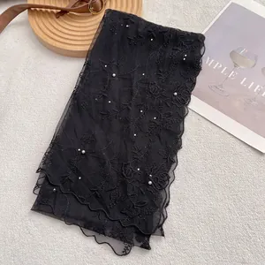 Detail of black lace scarf featuring floral embroidery and delicate pearl embellishments