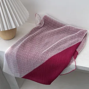 Close-up of pleated scarf featuring deep rose fabric and white polka dot mesh detail