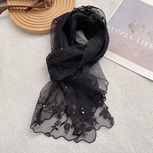 Detailed macro view of black lace scarf with floral embroidery and delicate pearls