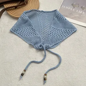 Detail of light blue crochet triangle scarf featuring knit texture and beaded strap accents