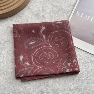 Detailed view of dark red paisley cotton bandana with rolled edges on a white fur rug