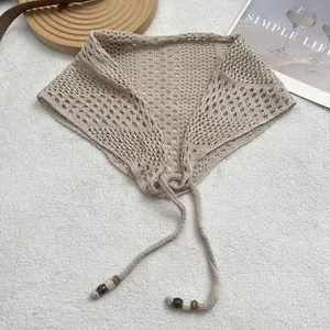 Detail of cream crochet lace shawl with hollow-out knit pattern and beaded tassel ties