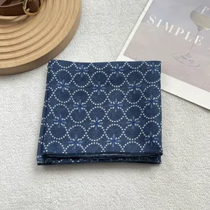 Detailed close-up of blue floral silk scarf featuring elegant dot pattern on a wooden tray