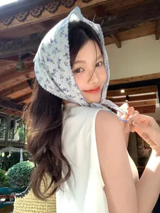 Dettaglio di una bandana vintage in cotone a fiori blu e strisce annodata tra i capelli