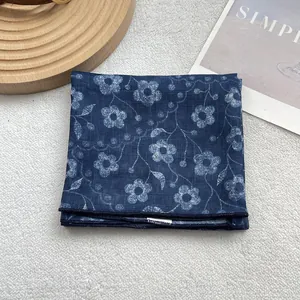 Detailed view of blue floral silk scarf fabric with delicate white flower pattern