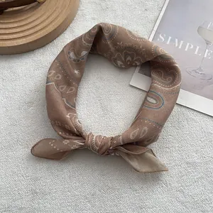Detailed close-up of brown paisley cotton linen scarf on minimalist cream background
