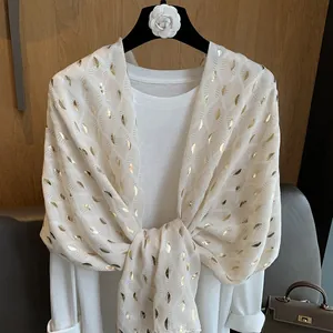 Detailopname van witte katoenen linnen sjaal met elegante goudfolie bladpatronen