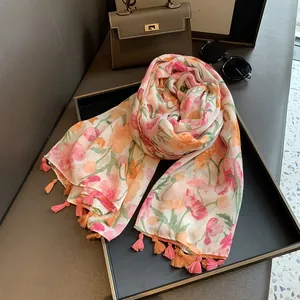 Détail d'une écharpe à fleurs avec fleurs roses et orange et bordure à pompons fins