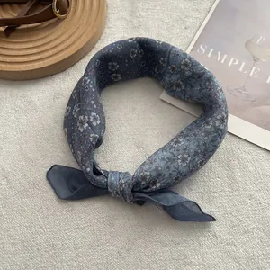 Detail of blue floral silk scarf with delicate white print on a minimalist aesthetic background