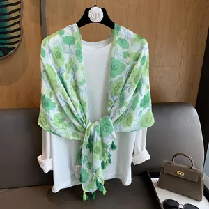 Détail de l'écharpe fleurie verte à pompons assortie à un haut blanc à manches longues