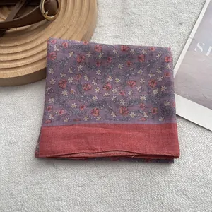 Close-up of vintage purple floral silk scarf with red border on a textured background